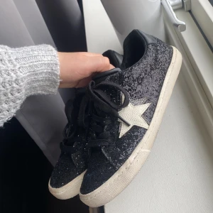 Svarta glitter sneakers med stjärnor  - Ett halvår gamla sneakers! Knappt använda men blir lätt smutsiga, dock enkelt att tvätta bort.  Nypris 550kr.