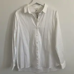 Vit skjorta från Object (köpt på Nelly.com), storlek 38. Helt oanvänd i nyskick. Lappen sitter kvar. Har 2 trådar som hänger från sömmarna (den var så när jag fick den). Köpt för 399kr säljer för 120kr