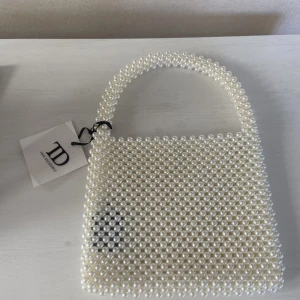 Pärlväska oanvänd med lapp kvar  - Ny oanvänd väska gjord i pärlor, lapp kvar. Skulle ha till ett bröllop men blev en annan. Kan skickas, finns annars i Sundbyberg Sthlm 