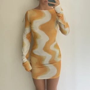 Gul klänning från NA-KD - Vit/gul mönstrad långärmad klänning från NA-KD med djup urringning vid ryggen💛passar perfekt till sommarens festivaler! Aldrig använd, med prislappar kvar