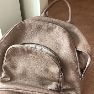 Roséguld färgad ryggsäck  - Liten Roséguld färgad ryggsäck  Helt oanvänd och i nyskick  Priset går att diskuteras.