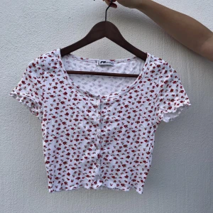 Coquette top - Söt coquette-top med rött blommotiv och knappdetaljer