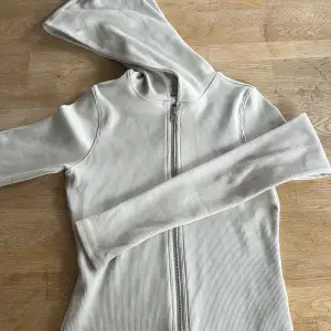 Denna cut tight zip hoodie från weekday blev aldrig en favorit därför säljs den. Koftan har  använts 1-2 gånger och är fortfarande i nyskick. Modellen är en figursyd kofta som är fint ribbad med en luva i färger beige.  Nypris 470kr💕