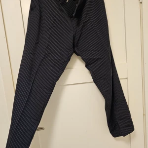 Boss kostymbyxs - Använd 1 gång vid bröllop. Nyskick, storlek 026. Jag är 32/30 och de är rätt i längd men något stora i midjan. Färgen är mörkt blå/svart med ljusblåa ränder