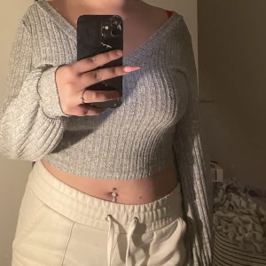 Grå tröja  - En jättesöt grå tröja med V-urringning som är använd en del men i superbra skick. Tröjan är lite puffig längst ner på armarna.