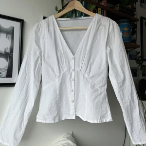 Blus från NA-KD - Söt vit blus från NA-KD i storlek S. Superfin till ett par blå jeans! Aningen gulnad vid vissa knappar (visas på bild 3). Inget man tänker på vid användning och går ev att få bort, har bara inte testat🤍