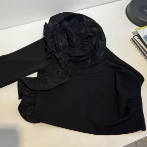 One shoulder topp - One shoulder topp med stor blomma på. Etiketten är kvar. Köpt på H&M. Storlek M