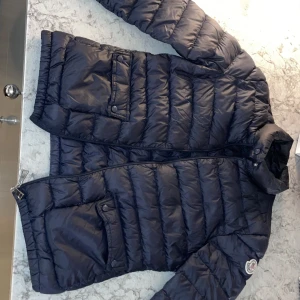 Moncler dunjacka - Väldigt fint skick, ser ut som ny! Mörkblå. Två fickor med knappar. Inköpspris: 10 620kr utgångspris nu: 7 300