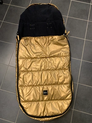 Brio varm  åkpåse Guld  - Hej   Säljer en nytvättad åkpåse från brio med måtten 41cm bred 95cm lång. 