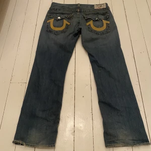True Religion Jeans - Feta true religion jeans i storlek 36 med feta bakfickor. Jeansen är i riktigt bra skick med nästan inget slitage mer än pytte lite heel drag. Skriv privat för fler bilder eller om du har några frågor.