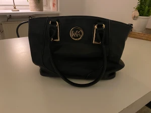 M/K väska ej äkta  - Använd rymlig väska med loggan M/K. Dragkedja på insidan sönder. I övrigt hel. 