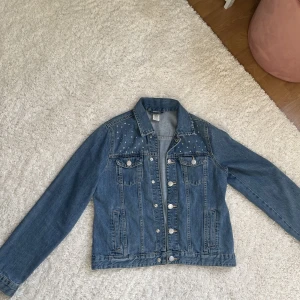 Jeans jacka - Säljer denna sjukt snygga jeansjacka från Lindex. Använd fåtal gånger med bling på bröstet. Vid fler frågor tveka inte att fråga.