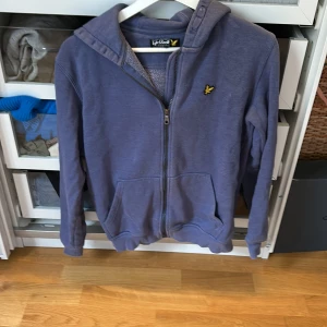 Lyle & scott zip up tröja  - En blå zip up tröja med luva från märket Lyle & scott. Lite nopprig. Säljs eftersom att den är för liten. 