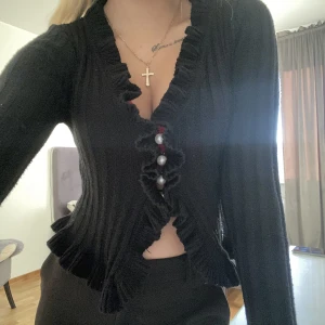 Svart kofta - En svart kofta med vita pärlor i mitten som en extra detalj, man kan välja att ha något under den men på bilden valde jag inte att ha det 😊