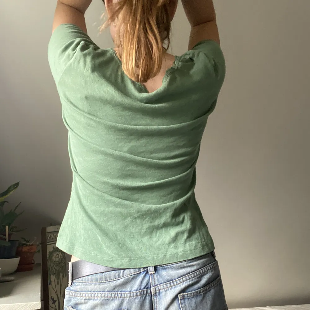 Säljer en grön tshirt från & other stories. Utöver spetsdetaljerna längst med halsen, så har toppen även små hjärtdetaljer på sig. Lappen säger strl. S, men den sitter löst på mig med storlek M.. T-paidat.