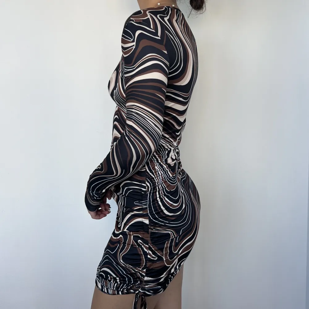 Kort klänning från Shein i mönstrad tyg av svart, vitt och brunt. Knytbara detaljer vid sidorna.. Klänningar.