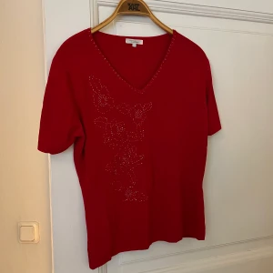 Röd vintage topp - Röd vintage topp som har ett blomtryck av pärlor på framsidan.  Storlek medium. Stretchigt material som lägger sig bra på kroppen. 