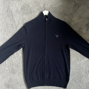 Gant Zip - Säljer denna Gant zip i färgen mörkblå, strlk M. Den är använd enbart ett fåtal gånger och är alltså i nyskick! Den är gjord på lambswool som liknar kashmir. Nypris: ca 1500kr, Mitt pris: 599kr. Hör av er vid frågor!