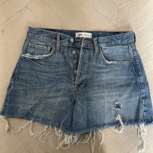 Jeansshorts - Slitna lågmidjade jeansshorts från Zara i storlek 38. Använda ett fåtal gånger, mycket bra skick. 