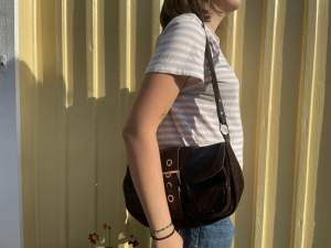En handväska i mocka och skinn, ganska mörk brun färg. Rymlig, men ser inte särskilt stor ut. Perfekt vardagsväska!⭐️ (frakt ingår inte i priset)