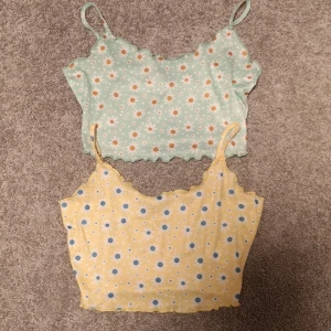 Toppar 2 pack - Supersöta croppade toppar i färgglatt blommigt mönster. Helt oanvända. Den gröna storlek 38(M) och den gula i 36(S). 