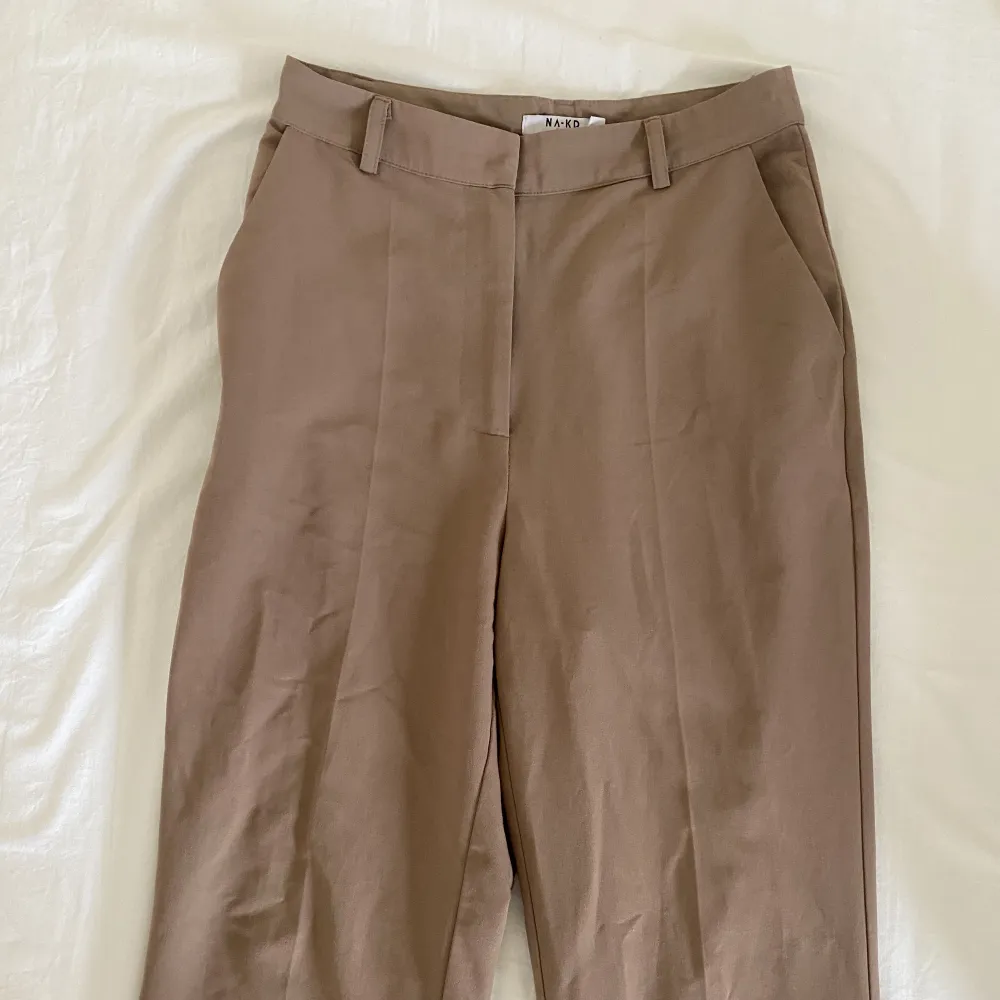 Jättesnygga bruna/ beiga kostymbyxor från Nakd. Benen är flared, det vill säga lite utsvängda! Aldrig använda då de är för stora för mig. . Jeans & Byxor.
