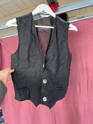 Väst - Cool väst med knytning som gör att du kan avgöra hur tajt/löst den ska sitta. Fint ordentligt material som behöver strykas, annars i nyskick. 