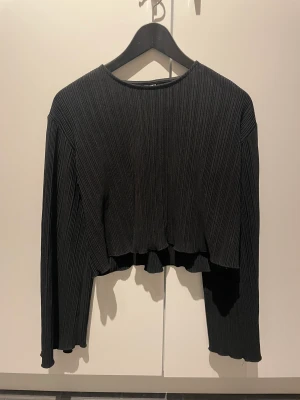 Svart festtopp - Svart glansig festtopp i ribbat stuk med vida armar. Pris kan diskuteras🤍