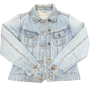 Oversized Vintage Jeansjacka - Varan kan köpas direkt på vår hemsida, ettmarke.se Märke: Vintage Modell: Oversize Färg: Ljuslå Storlek: Ingen storlekslapp finns. Men passar bäst personer som vanligtvis bär XS för att få jackan att sitta snyggt oversize. Axelbredd: 39 cm Ärmlängd: 45cm