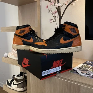 Jordan 1 Shattered Backboard 3.0 - Säljer mina Jordan 1’s i storlek EU 43. Sparsamt använda, orangea skosnören ingår.