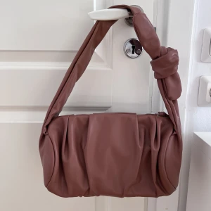 Väska - Brun väska från Nakd i nyskick! Väskan är i fake läder och har ett stort fack innehållande två mindre.  Mått: 28x15x15