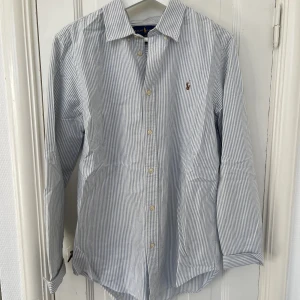 Blå och vit-randig skjorta från Ralph Lauren - Blå och vit-randig skjorta från Ralph Lauren i storlek 20. 