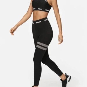Svarta stronger tights - Svarta träningstights från stronger med en vit rand på ena benet!