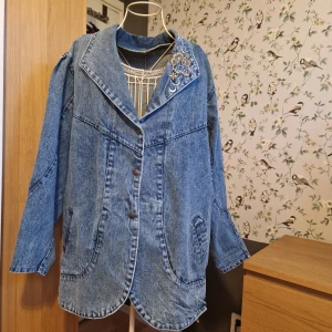 Jeans lång jacka 80-talet. - Vintage 80-talet blå dam jacka i grymt bra skick. Broderad ena krage. Konstruktionen i ryggen är nästan unik.  