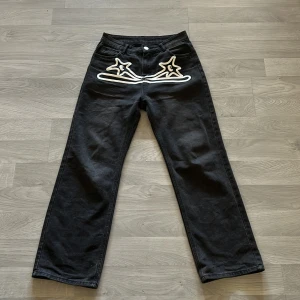 Y2k jeans - Svarta y2k byxor med snyggt tryck! Väldigt bäkväma. Condition:8,5/10 Strl:33/33