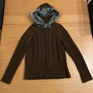 Zip-Up Hoodie med pälsluva - Väldigt fin zip-up, säljes enbart för att den är för liten för mig. En djup brun färg med den evigt 2000-tals kända pälsen. Skönt material, perfekt för vår och tidig sommar! M/L, mer åt M hållet! Skriv om du har frågor :) 