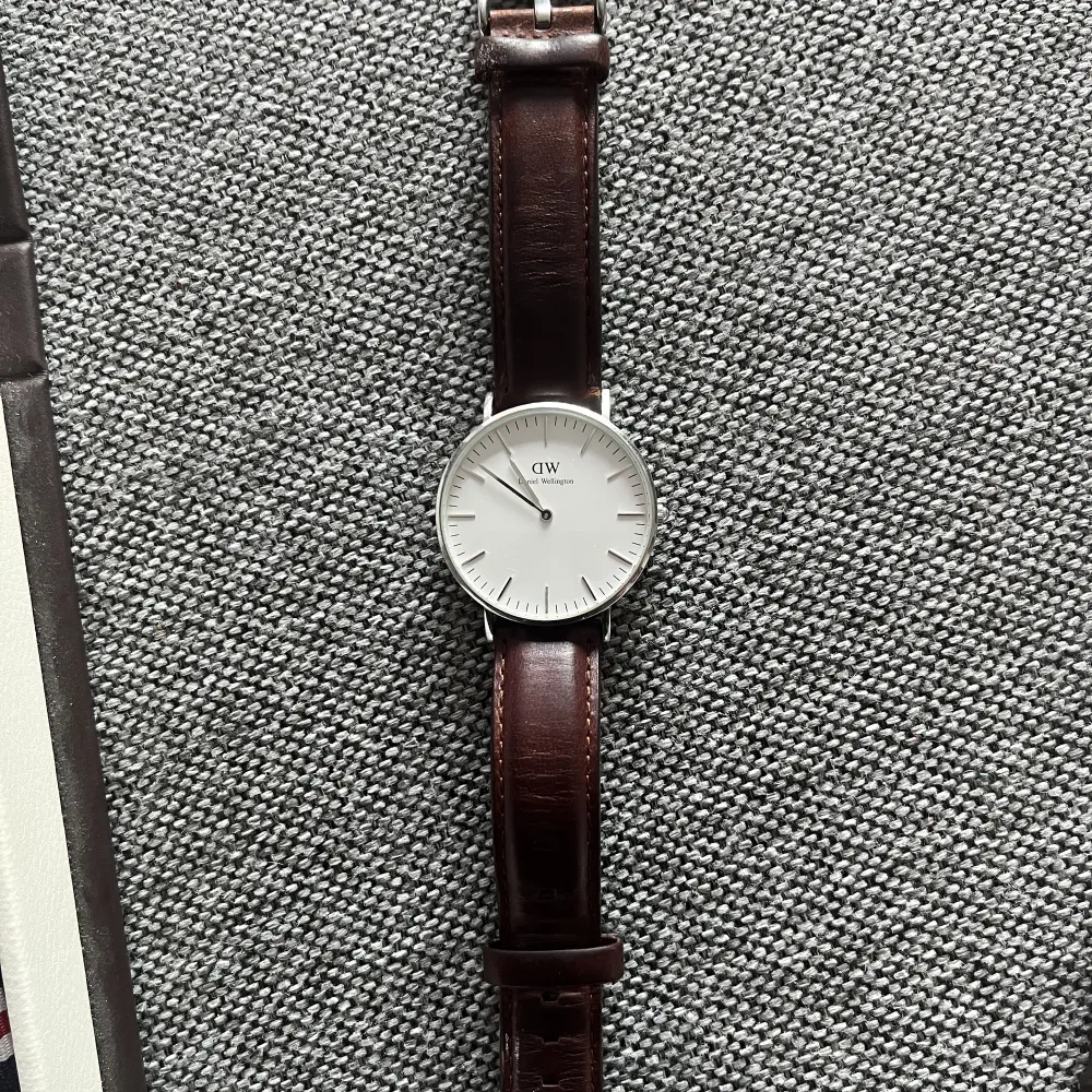 Äkta Daniel Wellington klocka. Silvrigt ur med brunt läder band, tillkommer även ett randigt band. Klockan är i ett mycket gott skick. 1000kr+frakt. Accessoarer.