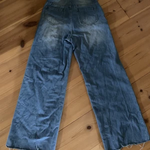 Jeans - Blå jeans med fåtal slitningar och vida ben. Storlek xxs och lite korta ben så rekommenderas till någon runt 165 cm och nedåt.