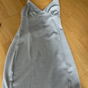 Tajt silverglittrig kort klänning med öppenrygg - Helt oanvänd supersnygg festlig klänning i silver. Perfekt nu till sommaren. Klänningen är öppen i ryggen.