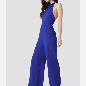 Blå byxdress - Helt oanvänd byxdress från na-kd med öppen rygg. Strl 34 men känns mer som 36/S. Ganska lång i benen, jag är 166 och den passar mig om jag har höga klackar.