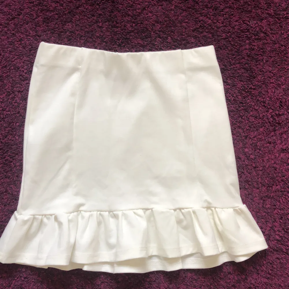 Tajt, vit och kort kjol med volang som formar sig efter kroppen. Bekväm. Oanvänd. Strl 158/164 för barn men känns som XS. . Kjolar.