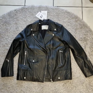 Skinnjacka från Selected Femme - Helt ny skinnjacka. Lappar sitter kvar, ny pris 2999 kr Oversized modell Dekorativa detaljer framtill Två fickor på sidorna Material: 100% Läder