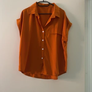 Orange blus - Orange blus med korta ärmar och v-ringning. Knappt använd. 