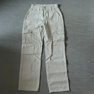 Cargobyxor - Beige cargobyxor. Väldigt fina och materialen är i super bra kvalite. Har bara haft på mig engång. Storleken är S men passar även XS. Längden är 107 cm. Midjastorlek är 66,5 cm. Höft storlek är 96,5 cm.