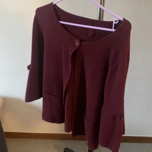 Vinröd tröja - En vinröd tröja med kvartalarmar och rosett på sidorna som ej kommer till användning 