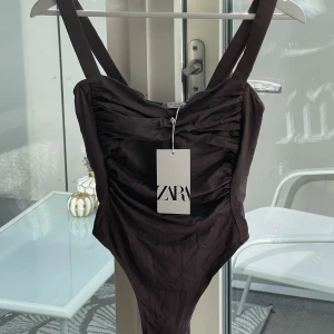 Body från ZARA - Sjuuuukt snygg body från Zara i typ brun/mauve (bild nr 2 gör färgen rättvis). Helt oanvänd med prislappen kvar!