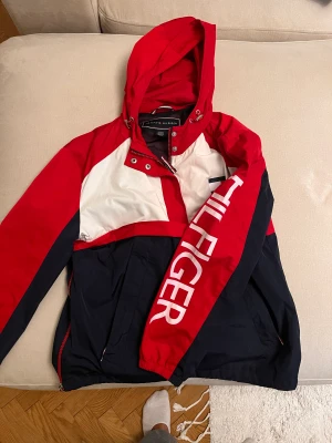 Tommy Hilfiger vindjacka - Tommy Hilfiger jacka inköpt i Usa för flera år sen. Använd under 5 gånger. Storlek S. Luva och två rymliga fickor