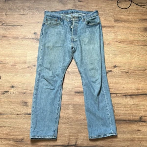 Levis 501 - Levis jeans i använt skick. De är i fint skick förutom slitningarna som syns på bilden som sitter mellan benen. De är förstärkta med en söm så inte slitaget ska bli värre men det är värt att veta om.