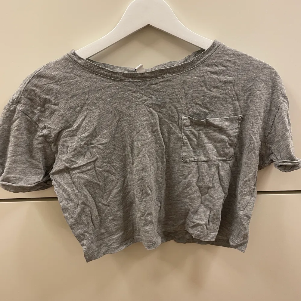 Fin grå croppad tshirt från hm med en liten ficka på bröstet. Bra skick. T-shirts.