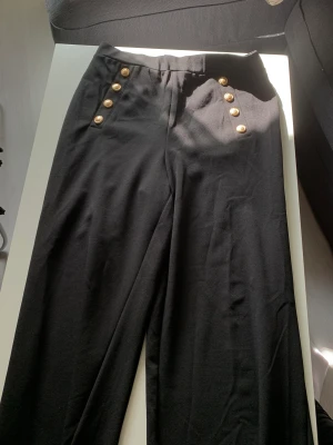 Svart stretch byxor med guldknappar - Perfekta byxor som passar till det mesta. De är lite stretch så bekvämt sitter dom allt minsann.